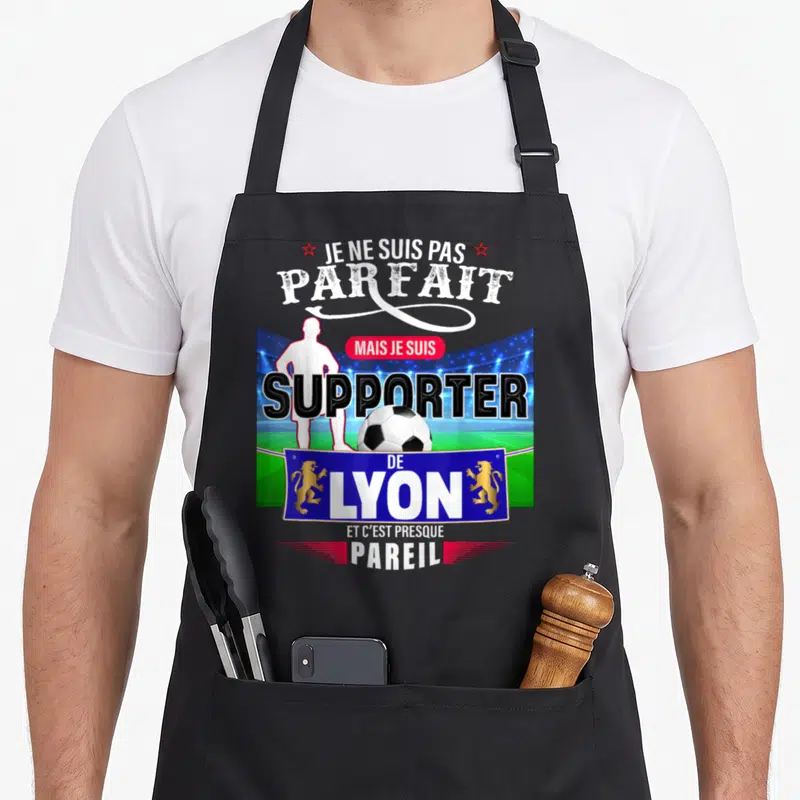 Tablier de cuisine noir avec illustration d'un supporter de Lyon et le texte Je ne suis pas parfait mais je suis supporter de Lyon.