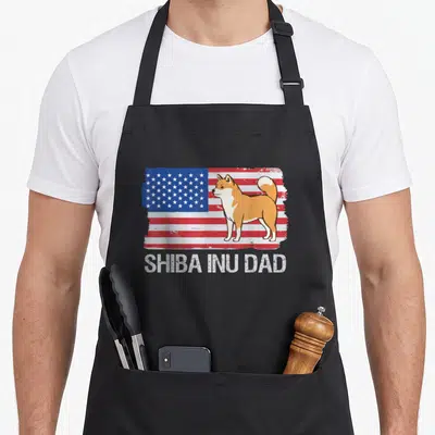 Tablier de cuisine noir avec illustration d'un Shiba Inu devant un drapeau américain et le texte Shiba Inu Dad en blanc.