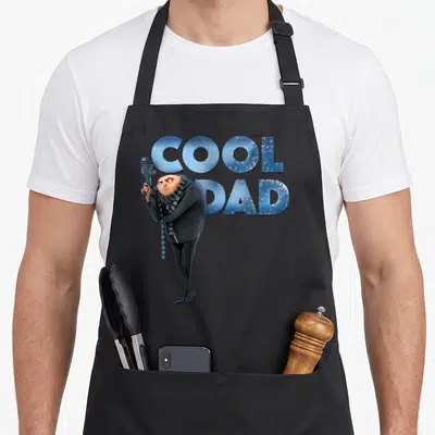 Tablier de cuisine noir avec Gru tenant un appareil et les mots Cool Dad en lettres glacées.