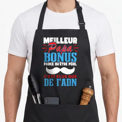 Tablier de cuisine noir avec l'inscription Meilleur Papa Bonus et une illustration de moustache blanche stylisée au centre du motif.