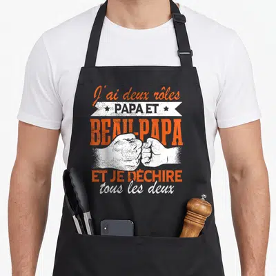 Tablier de cuisine noir avec inscription orange et blanche J'ai deux rôles papa et beau-papa et illustration de poings se serrant.