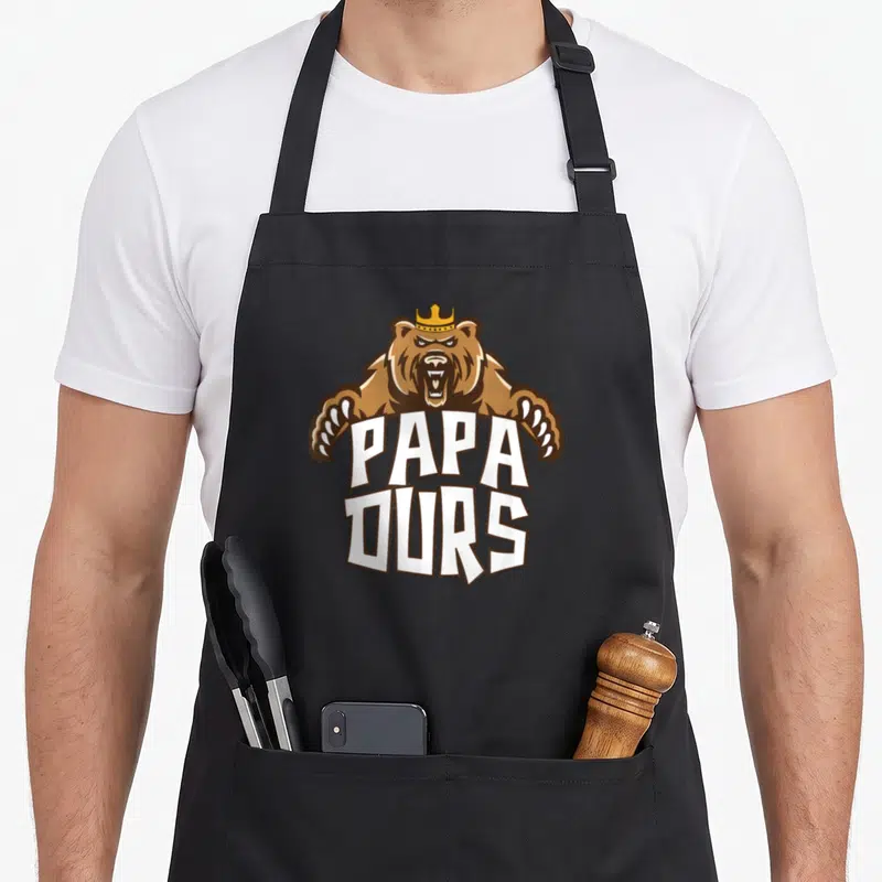 Tablier de cuisine noir avec un ours brun portant une couronne et les mots Papa Ours en grosses lettres blanches.