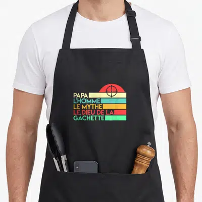 Tablier de cuisine noir avec motif retro couleur affichant Papa lhomme le mythe dieu de la gachette et une cible rouge.