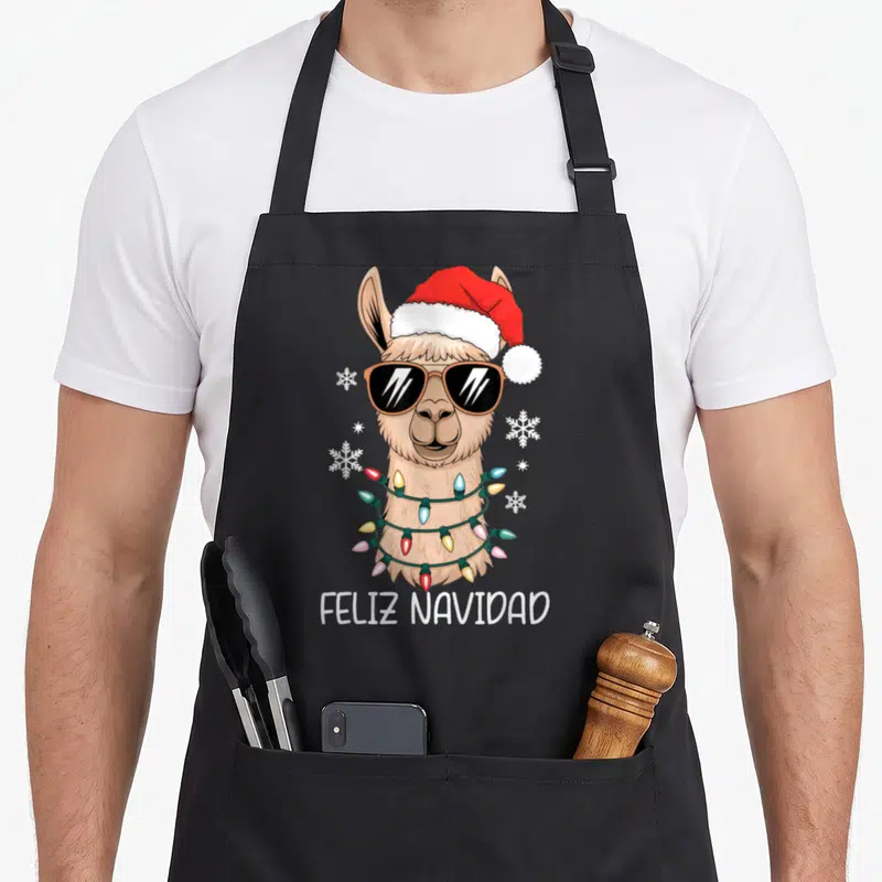 Tablier de cuisine noir avec un lama festif aux lunettes noires, une guirlande colorée et la mention Feliz Navidad imprimée en bas.