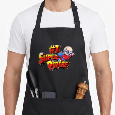 Tablier de cuisine noir avec illustration colorée d'un Pépère super-héros et le texte #1 Super Pépère en lettres stylisées.