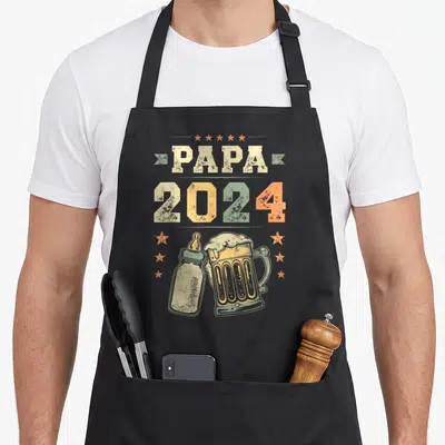 Tablier de cuisine noir avec illustration vintage d'un biberon et d'une grande bière sous l'inscription Papa 2024.