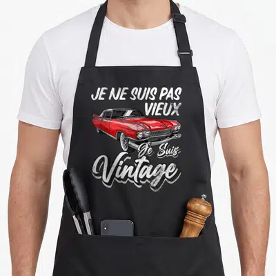 Tablier de cuisine noir avec inscription vintage et illustration de voiture américaine rouge classique.