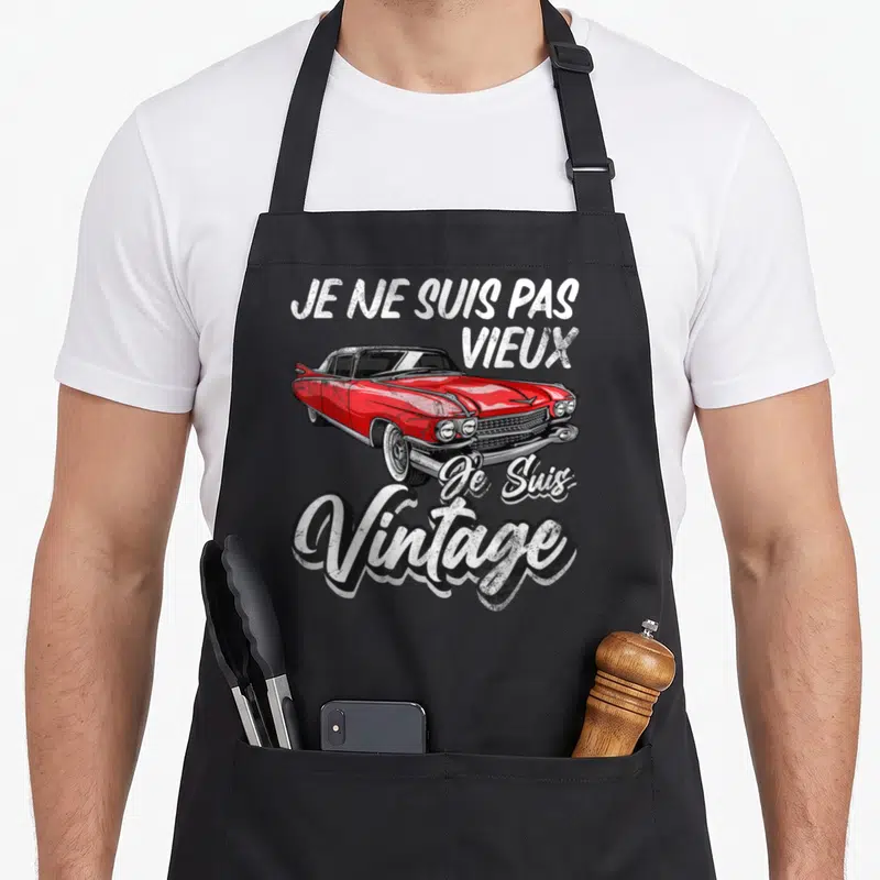 Tablier de cuisine noir avec inscription vintage et illustration de voiture américaine rouge classique.