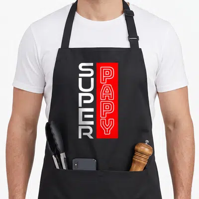 Tablier de cuisine noir avec inscription Super Papy en lettres blanches et rouges verticales.