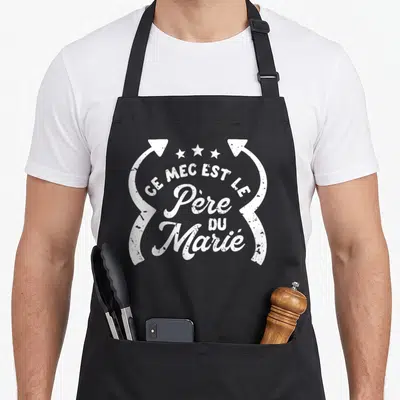 Tablier de cuisine noir avec l'inscription Ce mec est le Père du Marié en typographie blanche vintage encadrée d'arrows.