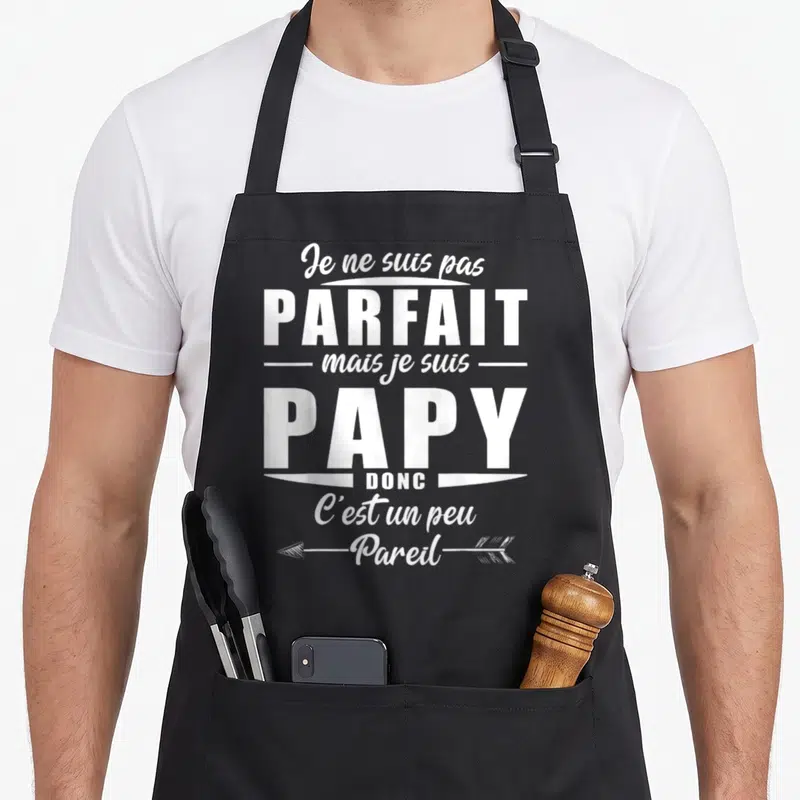 Tablier de cuisine noir avec le texte blanc Je ne suis pas parfait mais je suis papy donc c'est un peu pareil et une flèche décorative.