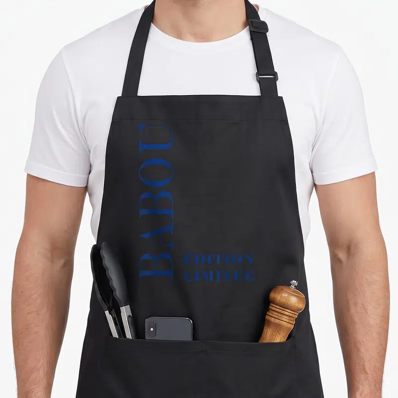 Tablier de cuisine noir avec inscription verticale BABOU et « ÉDITION LIMITÉE » en typographie bleue.
