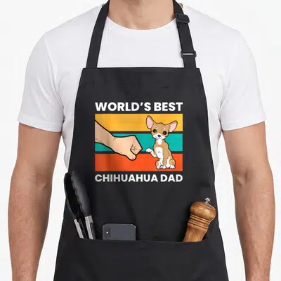 Tablier de cuisine noir avec illustration d'un chihuahua et une main effectuant un high-five sur bandes colorées.