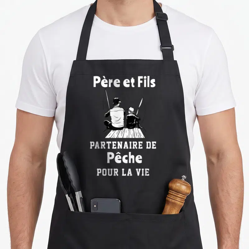 Tablier de cuisine noir avec illustration blanche d'un père et un fils assis en train de pêcher avec des cannes.