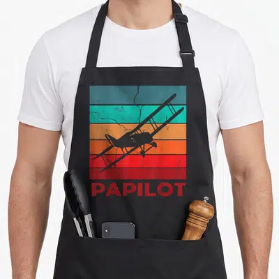 Tablier de cuisine noir avec silhouette biplan et mot Papilot en lettres rouges sur bandes colorées vintage.