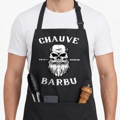 Tablier de cuisine noir avec illustration d'un crâne à longue barbe blanche et texte Chauve Barbu 100% Power