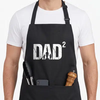 Tablier de cuisine noir avec inscription DAD² et silhouette blanche d'un père avec deux enfants.