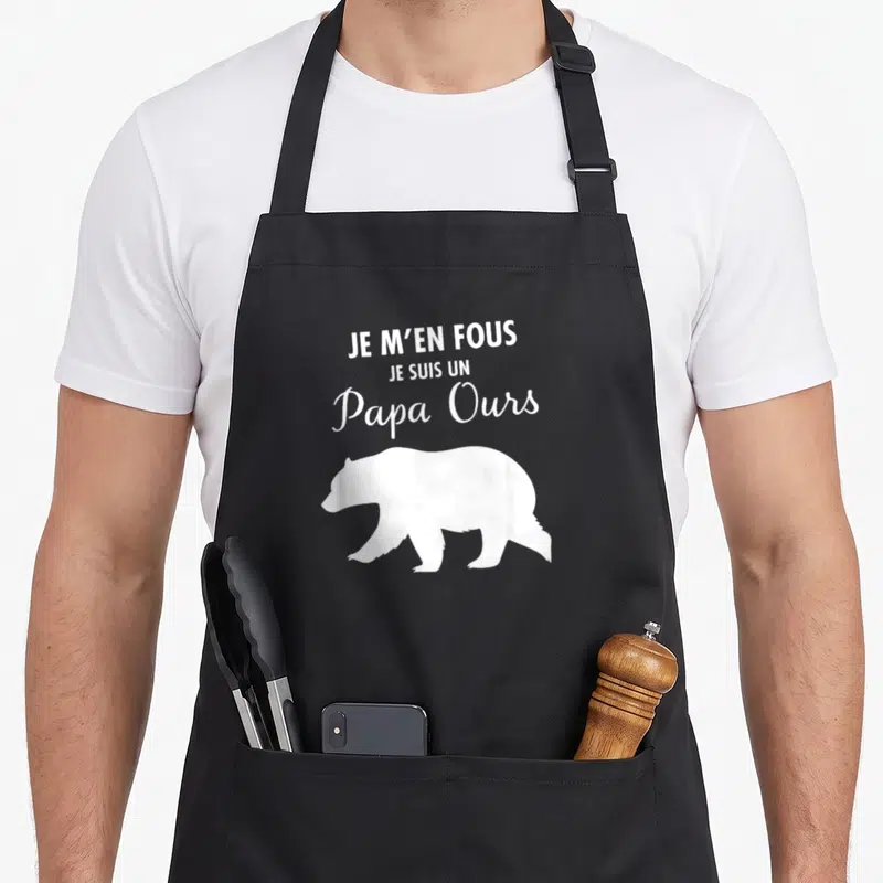 Tablier de cuisine noir avec inscription Je m'en fous je suis un papa ours et silhouette d'ours blanc en bas à droite.