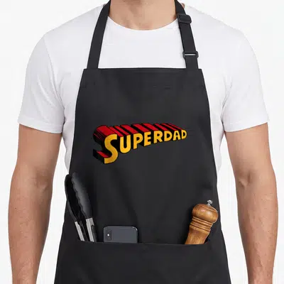 Tablier de cuisine noir avec l'inscription Superdad en typographie 3D rouge et jaune style comics.