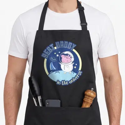 Tablier de cuisine noir avec Daddy Pig en tenue d'astronaute et l'inscription Best Daddy in the Universe sur fond bleu étoilé.