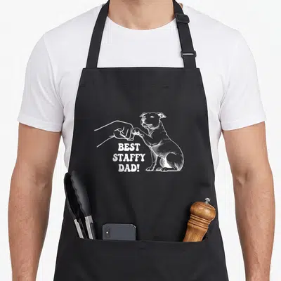Tablier de cuisine noir avec illustration blanche d'unStaffordshire terrier faisant un poing contre une main humaine.