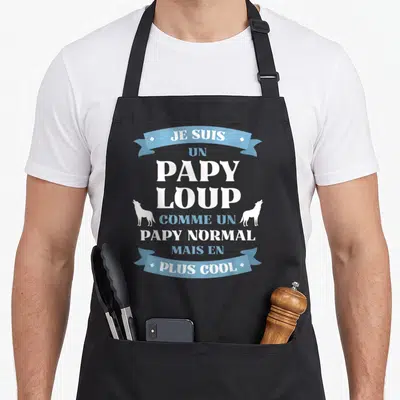 Tablier de cuisine noir avec l'inscription Je suis un papy loup et deux silhouettes de loups hurlants en bleu et blanc.