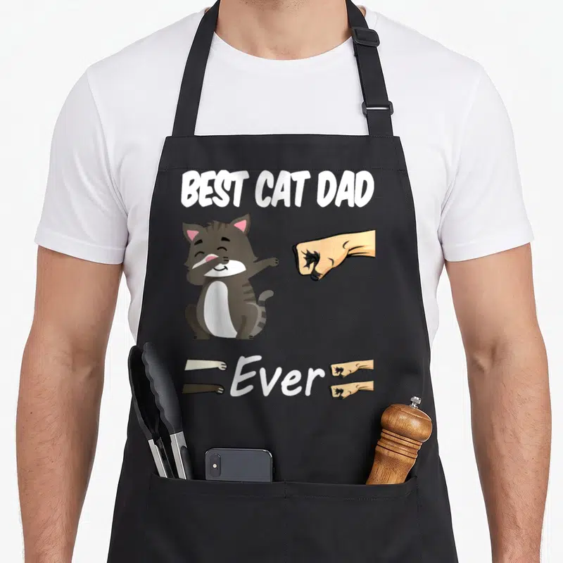 Tablier de cuisine noir avec illustration d'un chat gris et texte Best Cat Dad Ever en blanc.