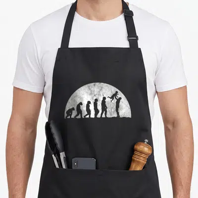 Tablier de cuisine noir avec une illustration grise représentant l'évolution humaine finissant par un père tenant un enfant en l'air.