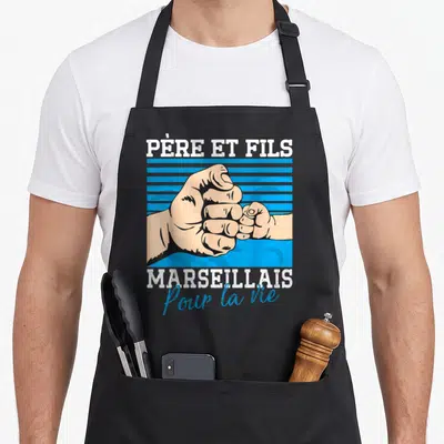 Tablier de cuisine noir avec une illustration de poignées de main et texte blanc et bleu sur fond rayé.