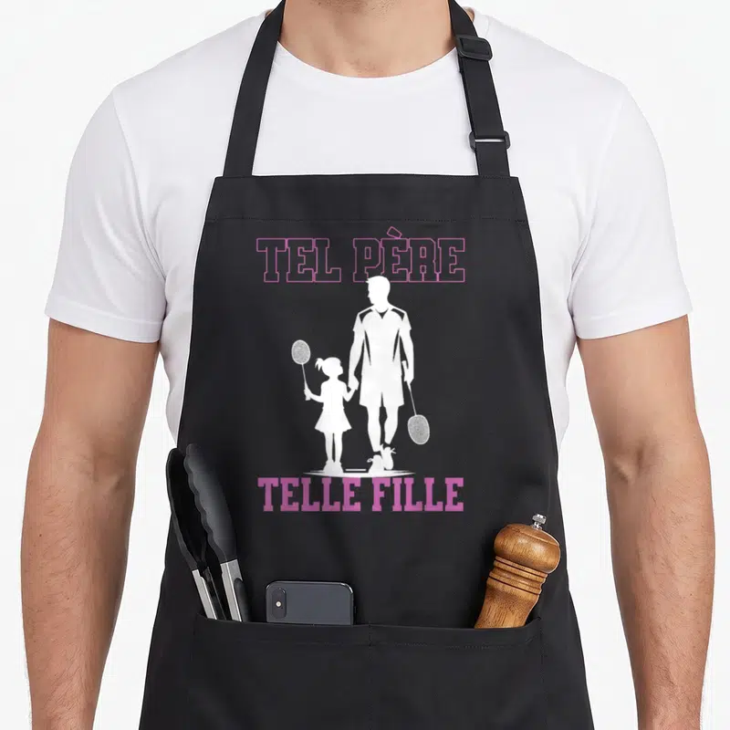 Tablier de cuisine noir avec silhouette blanche père et fille au badminton et texte Tel Père Telle Fille en rose.