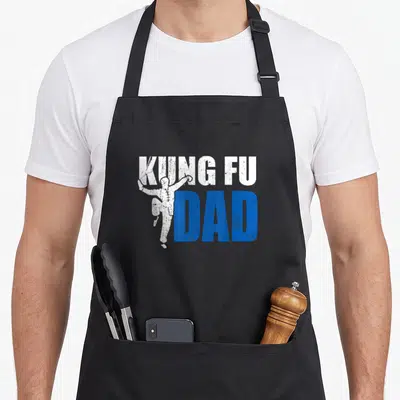 Tablier de cuisine noir avec l'inscription Kung Fu Dad et une silhouette de combattant en position de saut.