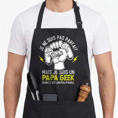 Tablier de cuisine noir avec une main tenant une manette et le texte Je ne suis pas parfait mais je suis un papa geek.