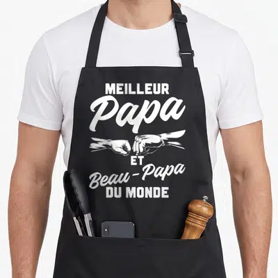 Tablier de cuisine noir avec inscription Meilleur Papa Et Beau-Papa Du Monde et deux poings se touchant en blanc.