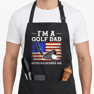 Tablier de cuisine noir avec illustration de club de golf sur fond de drapeau américain et texte blanc.