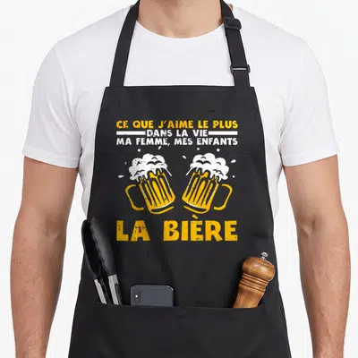 Tablier de cuisine noir avec deux verres de bière s'entrechoquant et texte humoristique en jaune et blanc.