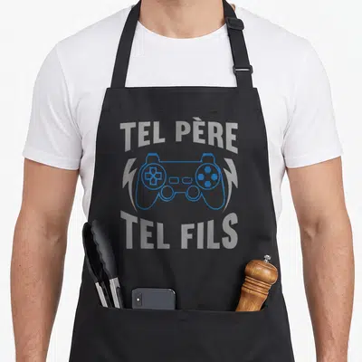 Tablier de cuisine noir avec manette bleue et texte Tel Père Tel Fils en gris clair.