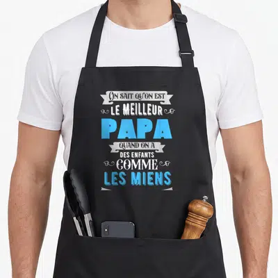 Tablier de cuisine noir avec inscription le meilleur papa quand on a des enfants comme les miens en bleu et blanc.