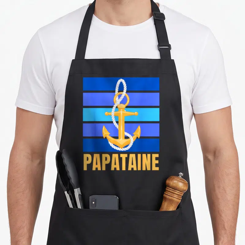 Tablier de cuisine noir avec ancre dorée, cordage blanc et inscription Papataine sur bandes bleues.