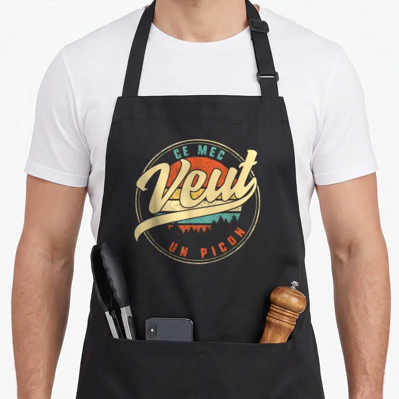 Tablier de cuisine noir avec logo circulaire vintage Ce Mec Veut Un Picon sur fond de soleil orange et turquoise.