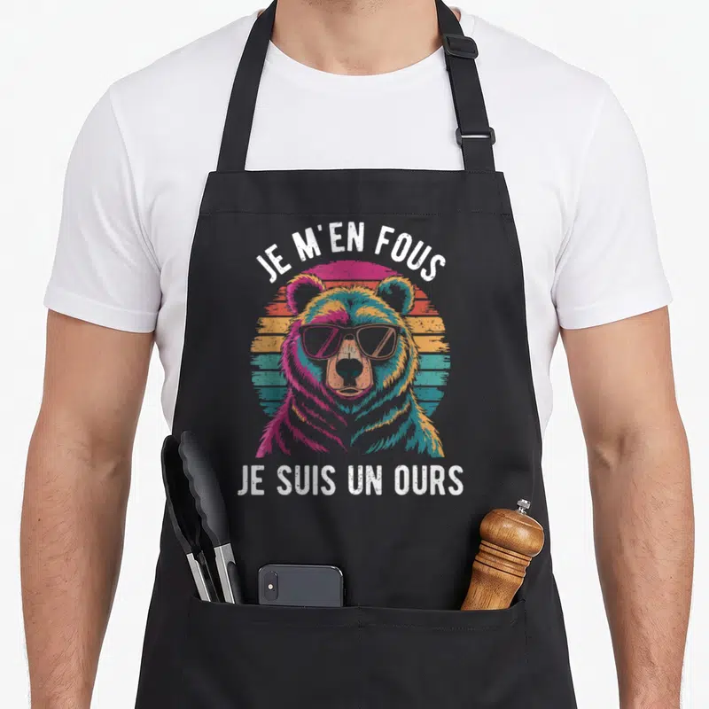 Tablier de cuisine noir avec un ours coloré portant des lunettes et le texte « Je m'en fous je suis un ours ».