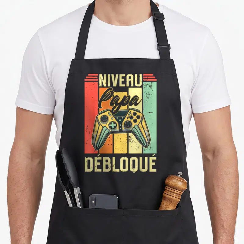 Tablier de cuisine noir avec illustration vintage manette de jeu et texte Niveau Papa Débloqué.