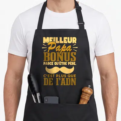 Tablier de cuisine noir avec inscription Meilleur Papa Bonus et une grande moustache dorée sur fond uni.