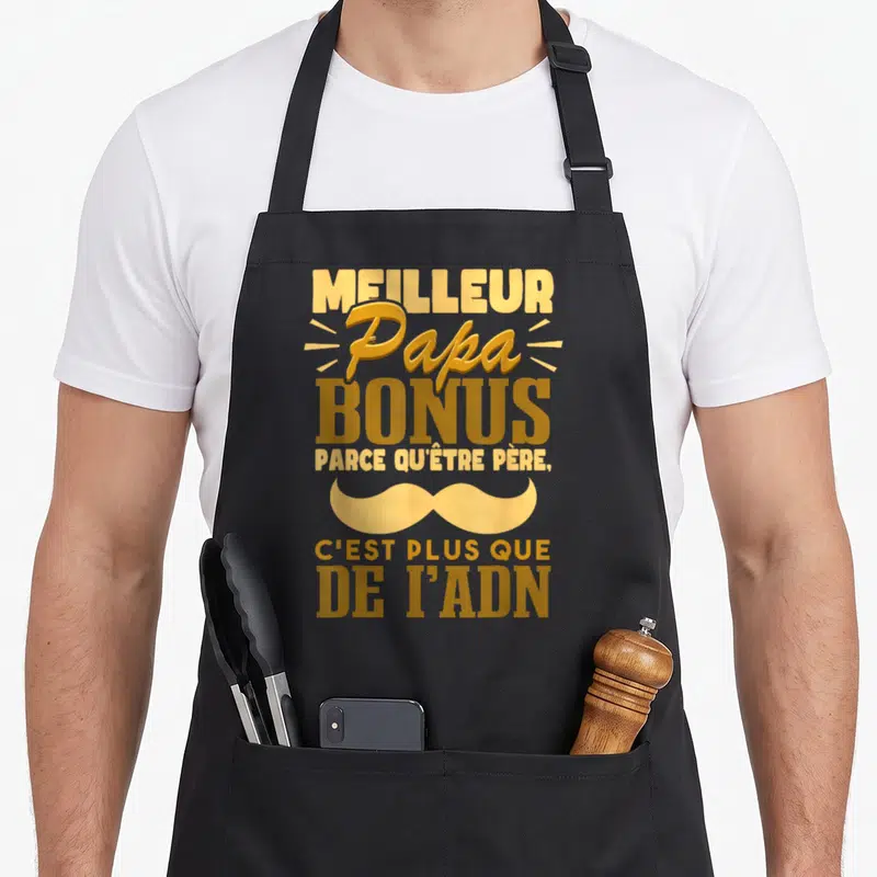 Tablier de cuisine noir avec inscription Meilleur Papa Bonus et une grande moustache dorée sur fond uni.