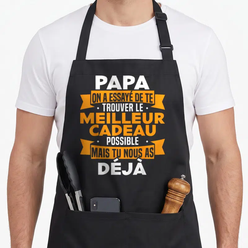 Tablier de cuisine noir avec une inscription blanche et orange sur fond gris mentionnant un message tendre pour papa.