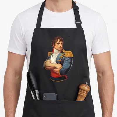 Tablier de cuisine noir avec illustration colorée de Napoléon Bonaparte les bras croisés en uniforme bleu et doré.