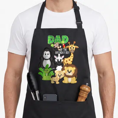 Tablier de cuisine noir avec DAD OF THE anniversaire BOY et animaux de zoo mignons comme un lion et une girafe.