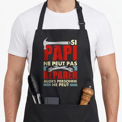 Tablier de cuisine noir avec inscription Si papi ne peut pas reparer et illustrations d'outils rouges et gris.