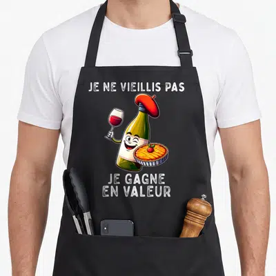 Tablier de cuisine noir avec une bouteille de vin en béret tenant un verre et une tarte aux pommes.