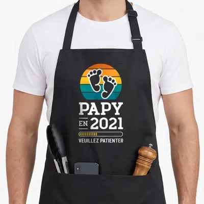 Tablier de cuisine noir avec motif Papy en 2021 Veuillez Patienter et deux petites empreintes de pieds colorées.