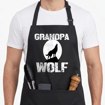 Tablier de cuisine noir avec silhouette de loup sur fond de lune et texte blanc vieilli Grandpa Wolf.